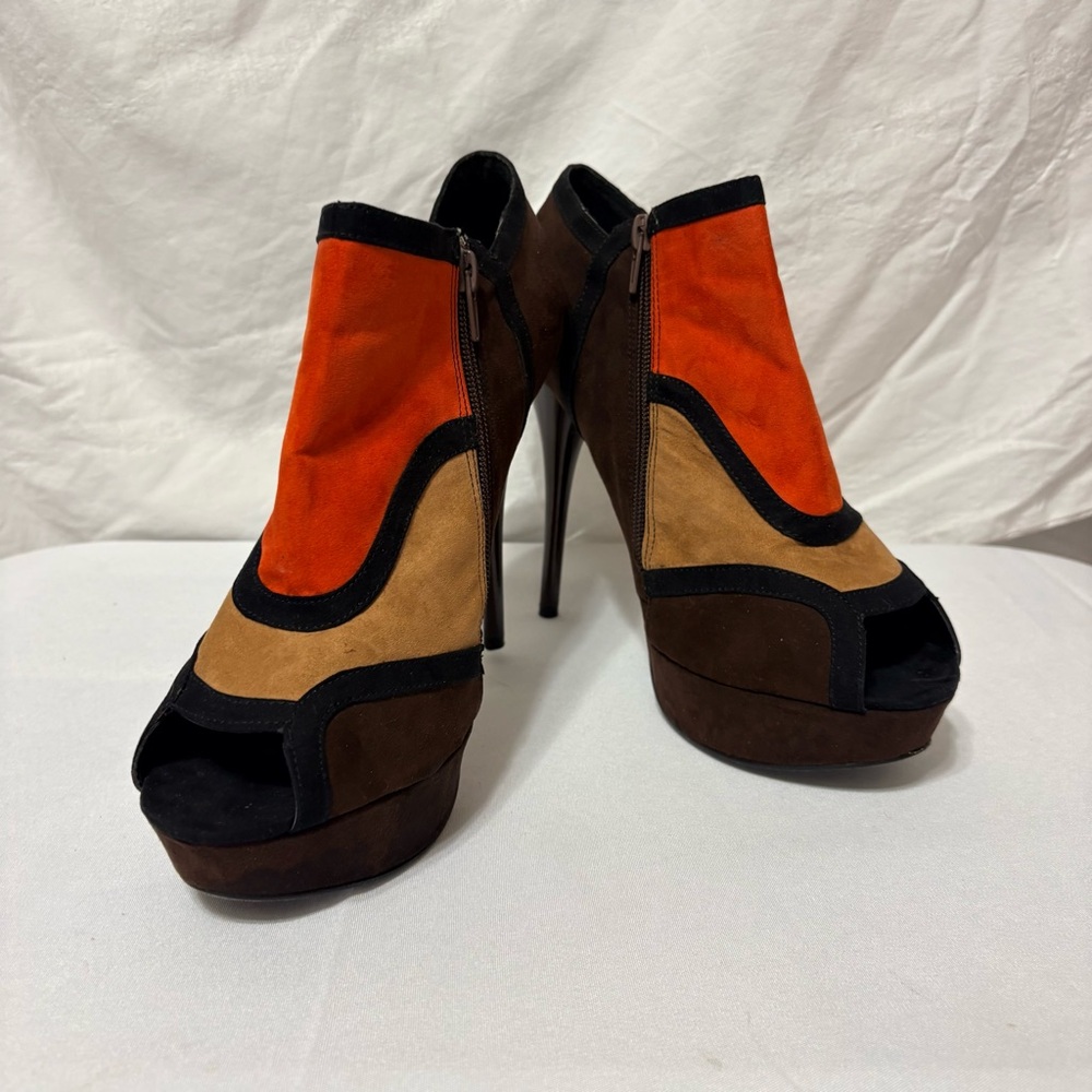 Colorblock ankle boots feature a striking orange, tan, and black suede design